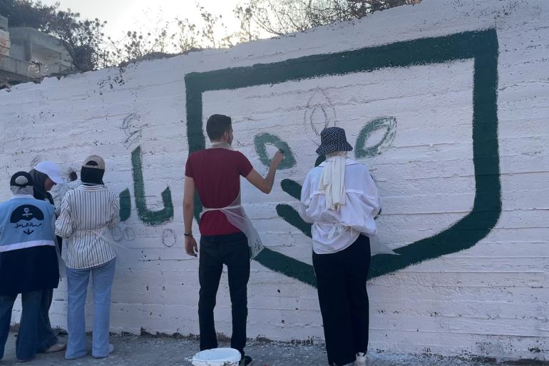 رسم شعار حملة بأيدينا نحييها على مدخل قرية قسطل معاف بريف اللاذقية.
