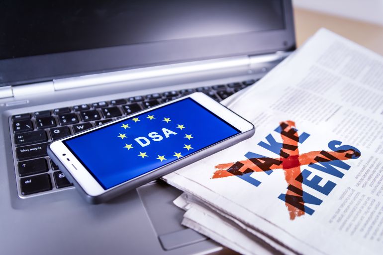 من يرسم حدود حرية الفضاء الرقمي في أوروبا؟ 3 Smartphone with DSA and EU flag on screen over a newspaper with Fake news and a laptop. Fake news, HOAX concept