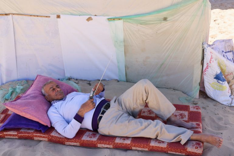 غزة بلا إذاعات.. من يملأ فراغ الأثير بعد أن أسكتته الحرب؟ 1 A displaced Palestinian, who fled his house due to Israeli strikes, lies down as he uses a radio to listen to the news at a tent camp, amid the ongoing conflict between Israel and the Palestinian Islamist group Hamas, in Rafah in the southern Gaza Strip, February 29, 2024. REUTERS/Saleh Salem