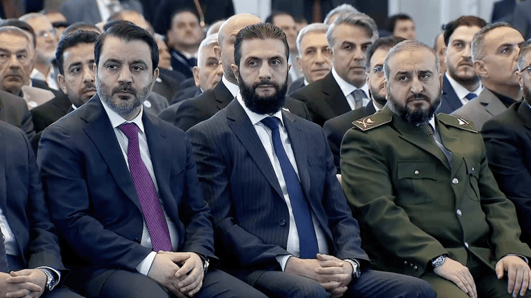 سوريا وسؤال الشرعية.. استبداد جديد أم ضرورات المرحلة؟ 2 من اليمين وزير الدفاع، ثم الشرع، ثم الشيباني - قصر الشعب المصدر: شاشة الجزيرة