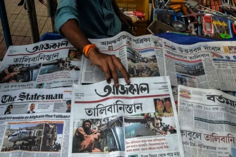 أفغانستان المجني عليها في الإعلام 5 A newspaper vendor sells and arranges newspapers displaying front page news about Afghanistan at roadside stall in Siliguri on August 17, 2021. featuring the front page news of conflicts in Afghanistan in Siliguri on August 17, 2021 after the Taliban's stunning military takeover of Afghanistan. (Photo by Diptendu DUTTA / AFP) (Photo by DIPTENDU DUTTA/AFP via Getty Images)