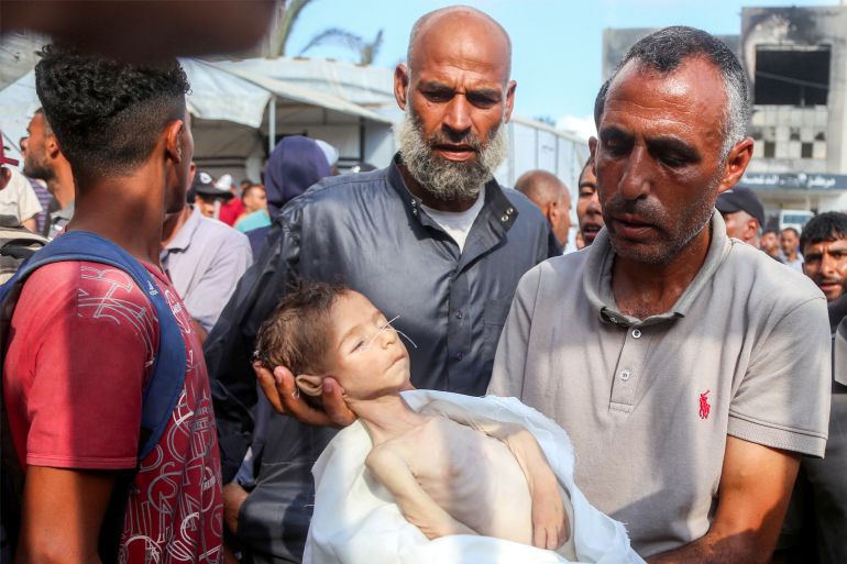 في غزة فقط يسقط الناس إغماء من الجوع ويموت الأطفال ببطء 2 EDITORS NOTE: Graphic content / TOPSHOT - The father of Yahya Fadi al-Najjar, an infant who died due to malnourishment, holds his body during the funeral at Nasser Medical Complex in Khan Yunis in the southern Gaza Strip on July 20, 2025.