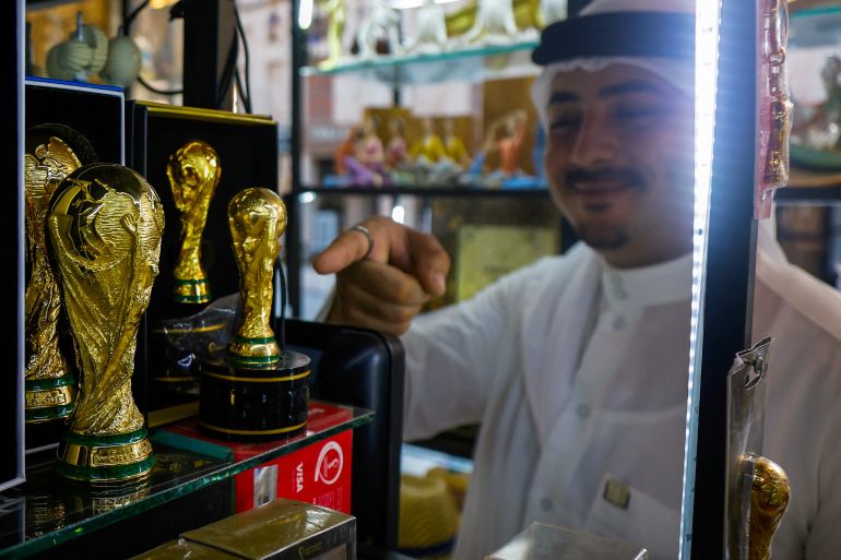 الأسبوع في صور 10 A man points to a replica of the Qatar 2022 World Cup trophy at a gift shop in Souq Waqif bazaar in Doha on July 24, 2025. (Photo by Karim JAAFAR / AFP)