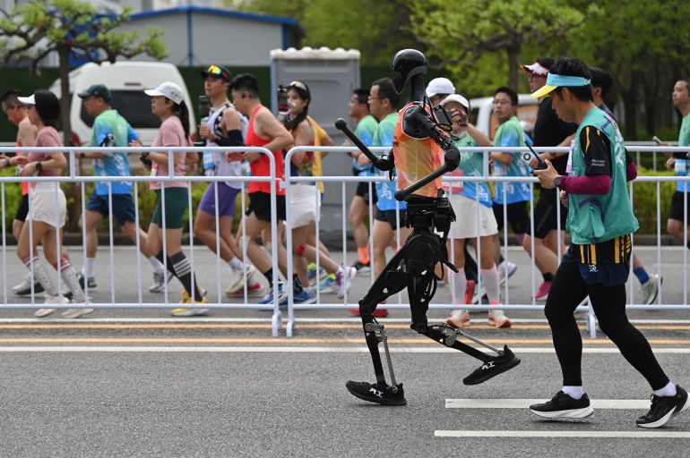 ما العلاقة بين ترامب والصعود الصاروخي لصناعة التقنية الصينية؟ 1 19 April 2025, China, Peking: The humanoid robot "Tian Gong" runs a half marathon with a coworker. In Beijing, humanoid robots competed against humans in a half marathon. Photo: Johannes Neudecker/dpa (Photo by Johannes Neudecker/picture alliance via Getty Images)