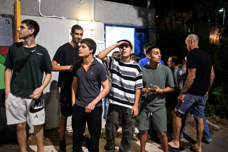 Israelis stand outside a public shelter as they look at interceptions of missiles fired from Iran towards Israel, at Haifa, Israel June 14, 2025. REUTERS/Rami Shlush ISRAEL OUT. NO COMMERCIAL OR EDITORIAL SALES IN ISRAEL