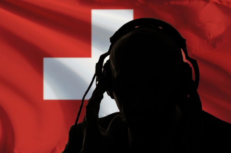 The silhouette of a man with headphones on the background of the flag of Switzerland eavesdropping on a conversation, a secret agent, a military intervention, a coup, an intelligence spy, a diplomat.