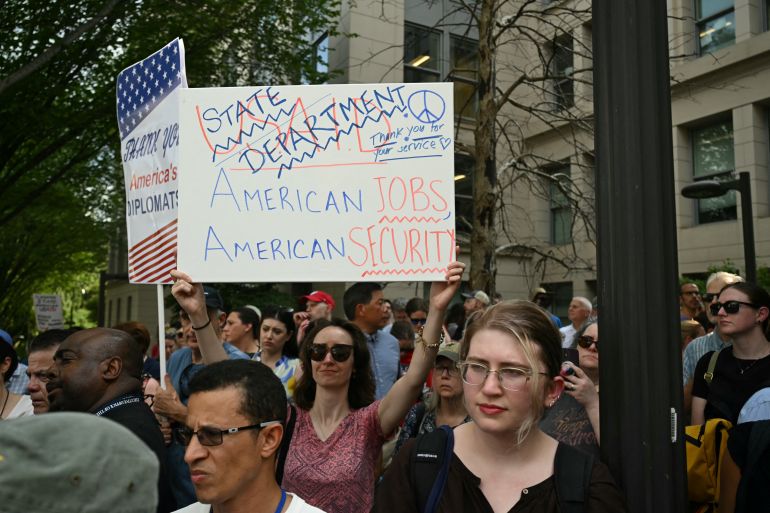 لماذا أقالت الخارجية الأميركية أكثر من 1300 موظف؟ 1 Supporters of fired US State Department workers hold signs outside the building in Washington, DC, on July 11, 2025. The US State Department began laying off more than 1,300 employees as part of President Donald Trump's campaign to massively downsize the federal government workforce. A State Department official said 1,107 members of the civil service and 246 Foreign Service employees were being informed that they were being fired. (Photo by SAUL LOEB / AFP)