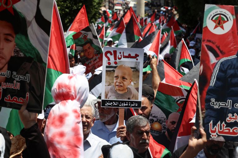 Demonstrators carry bloodied bundles and raise placards bearing pictures, during a protest in solidarity with the people of the Gaza Strip and Palestinian detainees, in the occupied-West Bank city of Ramallah on August 3, 2025. (Photo by Zain JAAFAR / AFP)