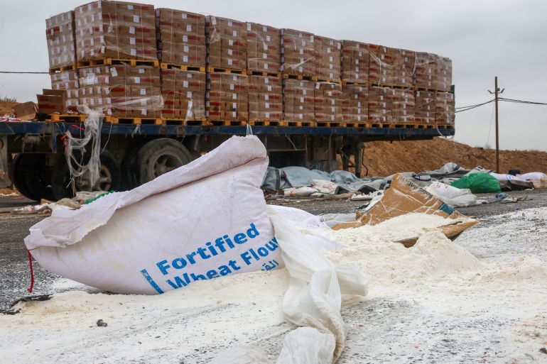 إسرائيل تعرقل المساعدات و تفاقم التجويع في غزة 1 Damaged humanitarian aid for Palestinians in Gaza lies scattered on the ground next to broken-down trucks near the border with the Gaza Strip, close to the Kissufim crossing in southern Israel, on August 13, 2025, amid the ongoing war with the Palestinian militant movement Hamas. (Photo by Jack GUEZ / AFP)