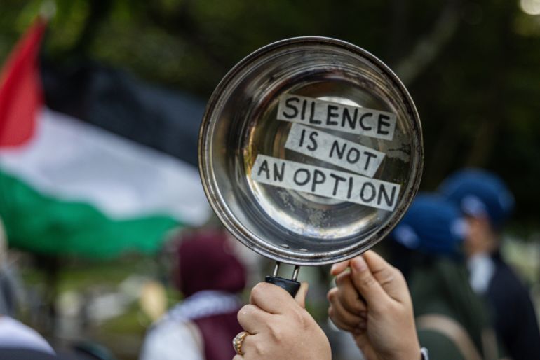 KUALA LUMPUR, MALAYSIA - AUGUST 02: A pro-Palestinian protester holds a pot symbolizing the hunger faced by Palestinian children during the war in Gaza, alongside a banner reading "Silence is Not an Option" during a march to express solidarity with the people of Palestine on August 2, 2025 in Kuala Lumpur, Malaysia. Protesters in Malaysia joined marches and actions globally, as pressure mounts on the Israeli government over a devastating humanitarian crisis unfolding as its war against Hamas continues. (Photo by Annice Lyn/Getty Images)