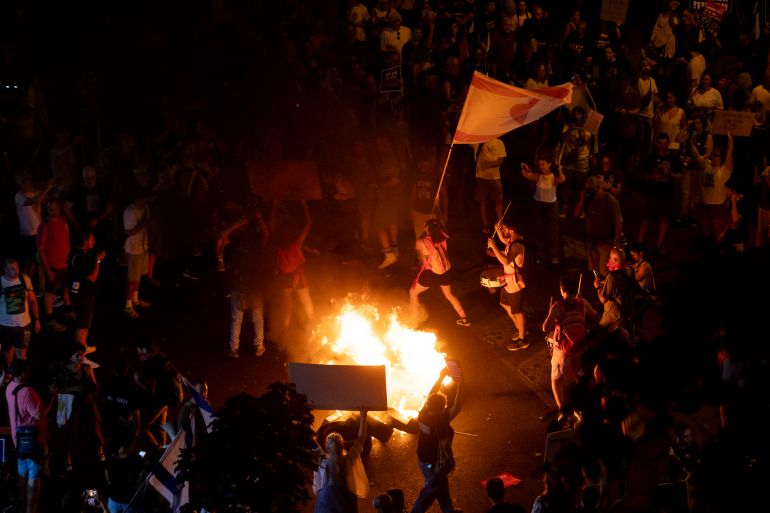 أبرز الصور في أسبوع.. غزة تحت حصار الموت ومظاهرات العالم تفضح التجويع 13 TEL AVIV, ISRAEL - AUGUST 7: Protesters set a fire as they hold signs and flags during a protest calling for a hostages deal on August 7, 2025 in Tel Aviv, Israel. Local media reports that Israeli Prime Minister Benjamin Netanyahu is seeking backing from his security cabinet for the "full occupation" of the Gaza Strip, despite warnings from security officials and human rights groups that such a move could further endanger the lives of hostages still believed to be held alive by Hamas, as well as Palestinians already suffering displacement and an acute hunger crisis in Gaza. (Photo by Amir Levy/Getty Images)