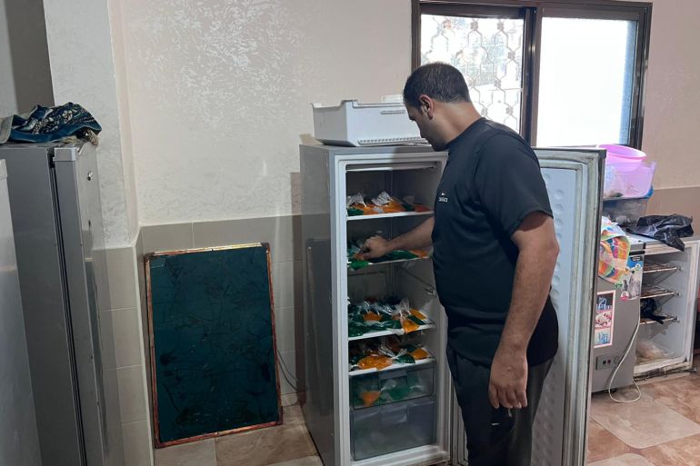 كيف يواجه الغزيون الحر الشديد وانقطاع الكهرباء في ظل الحرب؟ 1 المجدلاوي أثناء عمله في تعبئة ثلاجته بأكياس البراد لتبريدها (الجزيرة)