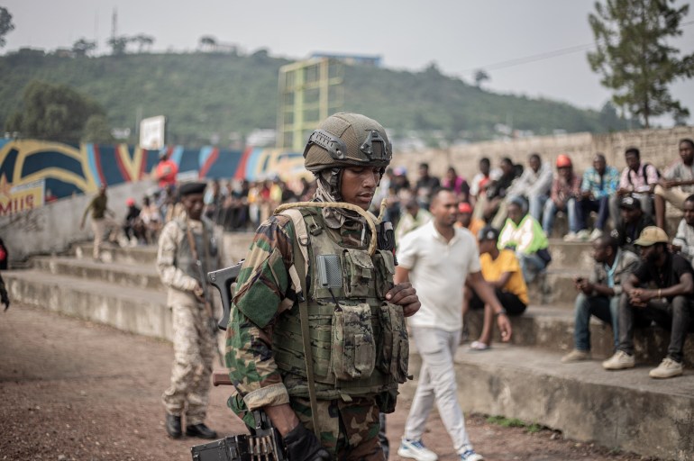 M23 soldiers are seen as a crowd gathers at the Stade de l'Unite'(Unity Stadium) in Goma on February 6, 2025 during a public gathering called by the armed group. Rwandan-backed M23 called its first public meeting on Thursday since seizing the Congolese city of Goma after deadly clashes, as its fighters advanced towards another regional capital. After capturing Goma, the main city in North Kivu province, last week, the M23 and Rwandan troops launched a new offensive on Wednesday in a neighbouring province. (Photo by Jospin mwisha / AFP)