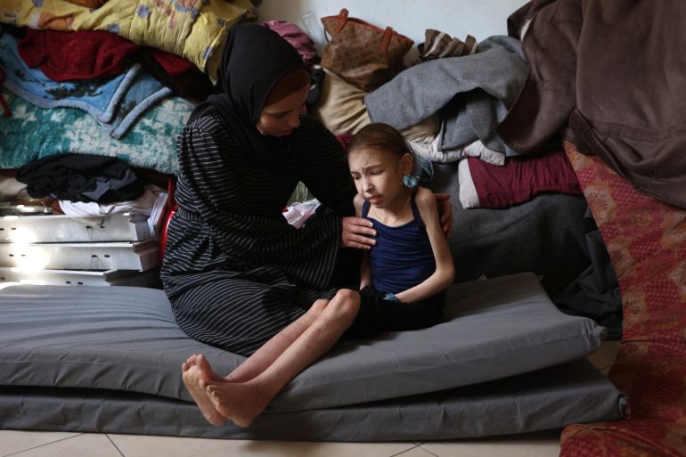 أجساد هزيلة وأعين غائرة.. أطفال غزة أول ضحايا المجاعة 20 Shuruq Ayyad consoles her 12-year-old daughter Rahaf, who is suffering from malnutrition, at a school-turned-shelter in al-Rimal in central Gaza City on May 4, 2025.