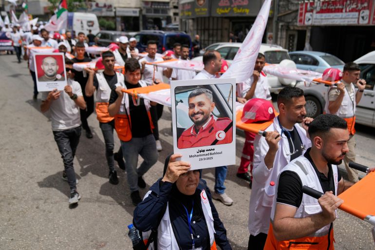 بالصور.. طواقم الهلال الأحمر تطالب بالحماية وسط غياب العدالة في غزة 20 A paramedic holds posters with names and pictures of fellow relief workers who lost their lives in the line of humanitarian duty, during a symbolic funeral for 48 fallen Palestinian Red Crescent Society members during the Israel Hamas war in Gaza, according to a PRCS statement, marking the World Day of Red Cross and Red Crescent, in the West Bank city of Ramallah Monday, May 12, 2025. (AP Photo/Nasser Nasser)