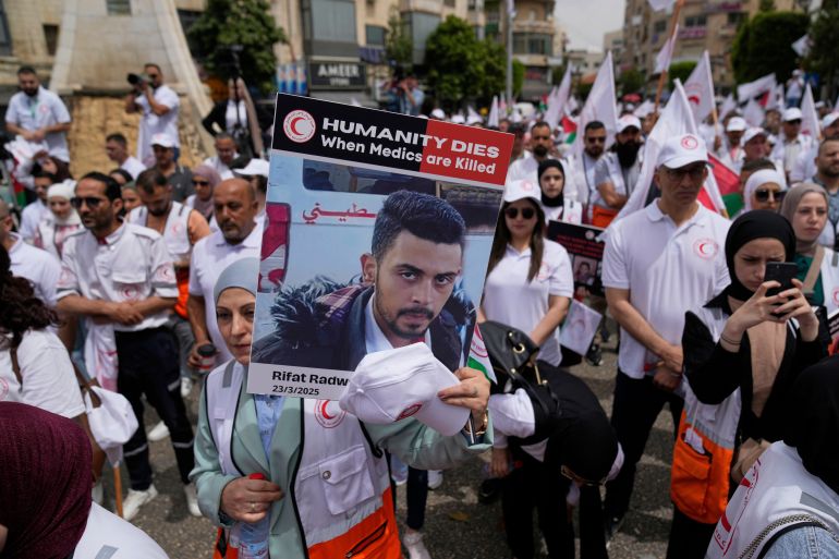 بالصور.. طواقم الهلال الأحمر تطالب بالحماية وسط غياب العدالة في غزة 24 Paramedic hold posters with names and pictures of fellow relief workers who lost their lives in the line of humanitarian duty, during a symbolic funeral for 48 fallen Palestinian Red Crescent Society members during the Israel Hamas war in Gaza, according to a PRCS statement, marking the World Day of Red Cross and Red Crescent, in the West Bank city of Ramallah Monday, May 12, 2025. (AP Photo/Nasser Nasser)