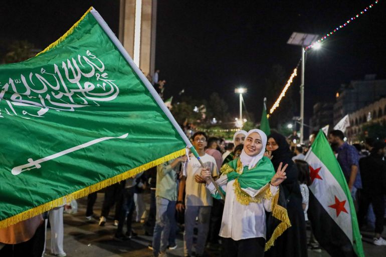 بالصور.. كيف تفاعل السوريون مع قرار رفع العقوبات الأميركية؟ 23 A girl holds a Saudi flag in celebration after U.S. President Donald Trump announced plans during his visit to Saudi Arabia to ease sanctions on Syria and normalize relations with its new government, in Homs, Syria, late Tuesday, May 13, 2025.(AP Photo/Omar Albam)