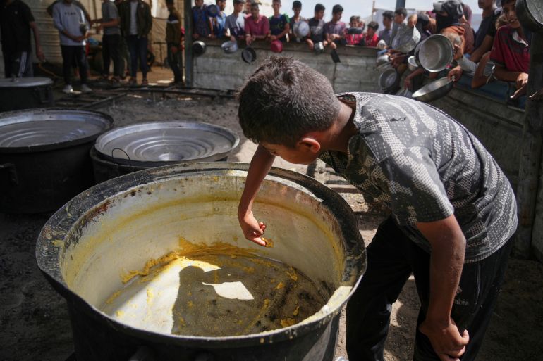 غزة تختنق.. جوع وموت ودمار في قبضة الاحتلال 20 A boy scrapes leftovers from an empty pot after all the meals were distributed at a community kitchen in Khan Younis, southern Gaza Strip, Wednesday, May 14, 2025. (AP Photo/Abdel Kareem Hana)