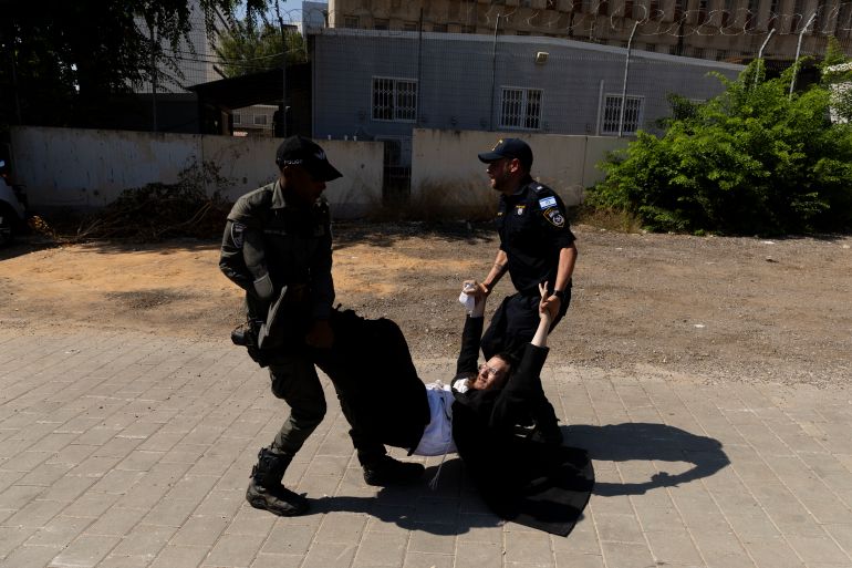 حملة لاعتقال الحريديم الفارين من الخدمة وقادتهم يهددون بإسقاط الحكومة 21 RAMAT GAN, ISRAEL - AUGUST 5: Police officers disperse an an Ultra Orthodox Jewish protester during a demonstration against drafting to the Israeli military near a recruitment base on August 5, 2024 in the Tel HaShomer area of Ramat Gan, Israel. Hundreds of Ultra-Orthodox men who were previously exempted from military service were due to arrive at the recruitment office here today, following a Supreme Court ruling that ended the exemption for yeshiva students. (Photo by Amir Levy/Getty Images)