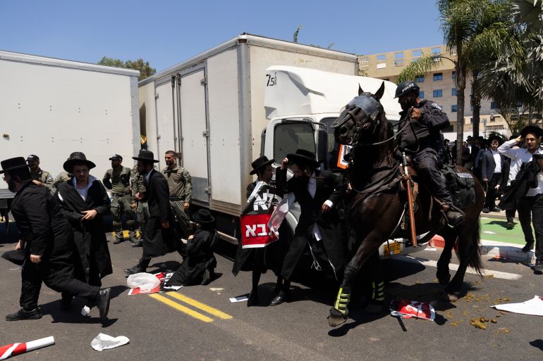 حملة لاعتقال الحريديم الفارين من الخدمة وقادتهم يهددون بإسقاط الحكومة 20 RAMAT GAN, ISRAEL - AUGUST 5: Ultra-Orthodox Jewish men clash with mounted police officers during a demonstration against drafting to the Israeli military near a recruitment base on August 5, 2024 in the Tel HaShomer area of Ramat Gan, Israel. Hundreds of Ultra-Orthodox men who were previously exempted from military service were due to arrive at the recruitment office here today, following a Supreme Court ruling that ended the exemption for yeshiva students. (Photo by Amir Levy/Getty Images)