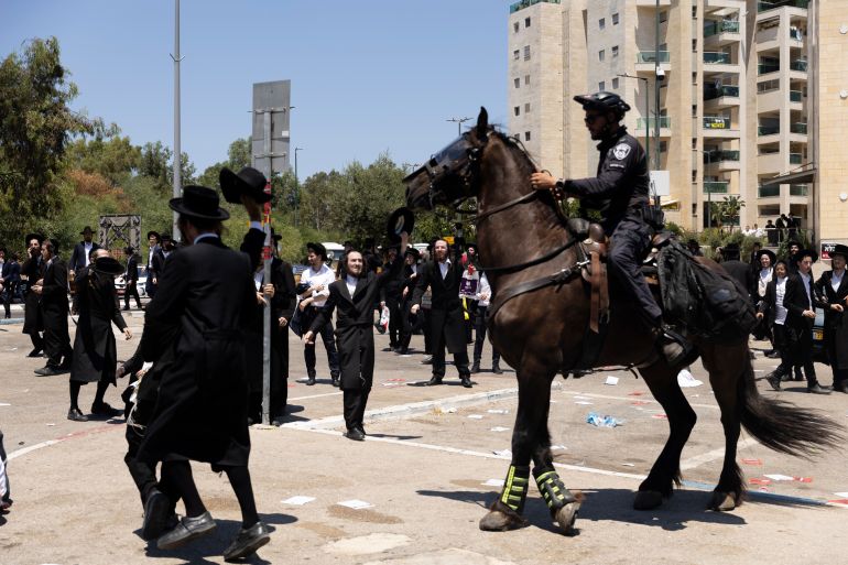 حملة لاعتقال الحريديم الفارين من الخدمة وقادتهم يهددون بإسقاط الحكومة 23 RAMAT GAN, ISRAEL - AUGUST 5: Ultra-Orthodox Jewish men clash with mounted police officers during a demonstration against drafting to the Israeli military near a recruitment base on August 5, 2024 in the Tel HaShomer area of Ramat Gan, Israel. Hundreds of Ultra-Orthodox men who were previously exempted from military service were due to arrive at the recruitment office here today, following a Supreme Court ruling that ended the exemption for yeshiva students. (Photo by Amir Levy/Getty Images)