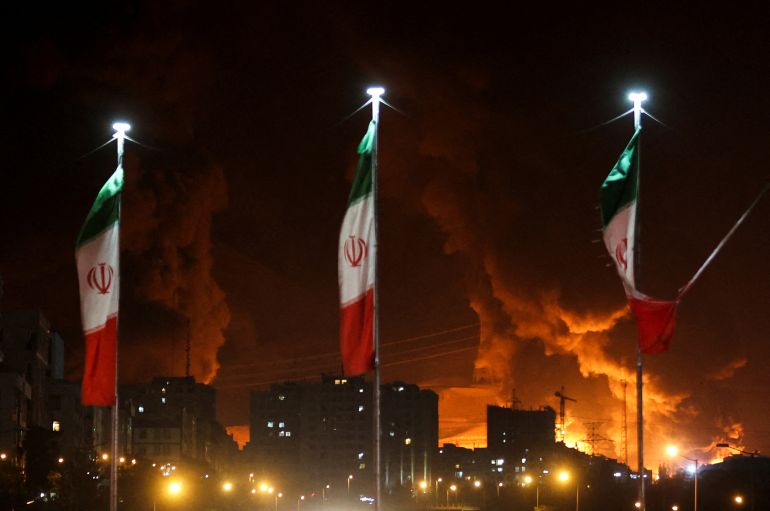 هل سيطر نتنياهو على سماء طهران فعلاً؟ 1 Iranian flags fly as fire and smoke from an Israeli attack on Sharan Oil depot rise, following Israeli strikes on Iran, in Tehran, Iran, June 15, 2025. Majid Asgaripour/WANA (West Asia News Agency) via REUTERS ATTENTION EDITORS - THIS PICTURE WAS PROVIDED BY A THIRD PARTY TPX IMAGES OF THE DAY