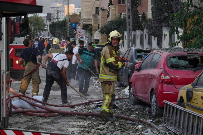 الجزيرة نت ترصد تفاعل الشارع الإيراني مع الضربة الإسرائيلية 1 Firefighters and people clean up the scene of an explosion at a residence compound after Israeli attacks in Tehran, Friday, June 13, 2025. (AP Photo/Vahid Salemi)