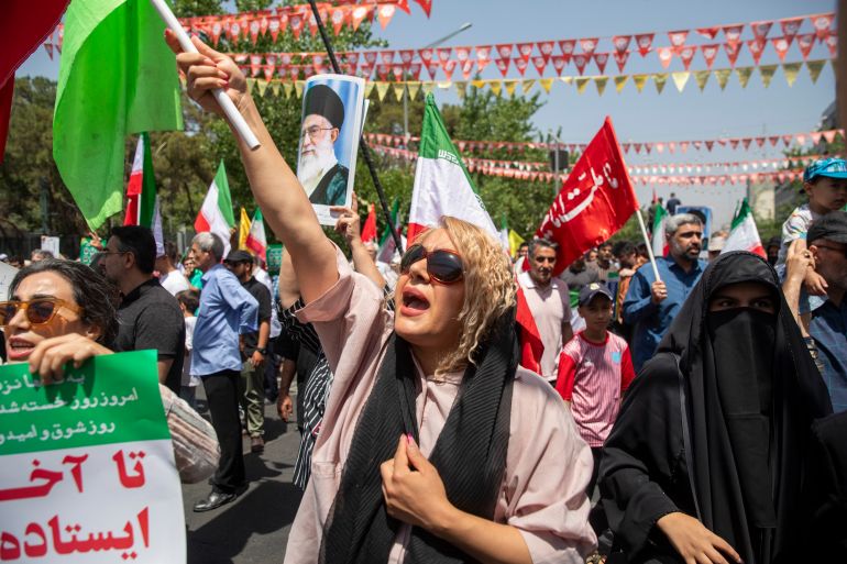 هل انتهت حرب الـ12 يوما بين إسرائيل وإيران؟ وما مكاسب كل طرف؟ 1 TEHRAN, IRAN - JUNE 20: Demonstrators wave Iranian flags as one holds up a poster of Iran's Supreme Leader Ayatollah Ali Khamenei during a protest against Israeli attacks on Iran, after the Friday prayer ceremonies on June 20, 2025 in central Tehran, Iran. Over recent days, Iran has been hit by a series of Israeli airstrikes targeting military and nuclear sites, as well as top military officials, prompting Iran to launch a counterattack. (Photo by Majid Saeedi/Getty Images)