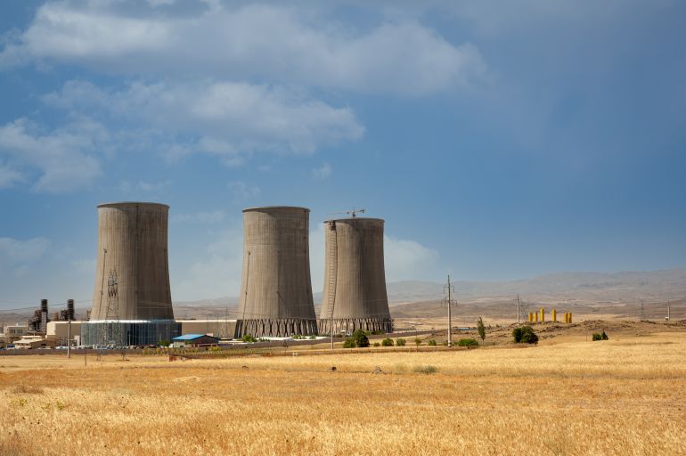 كتاب “جيوبوليتيك”: منع الغرب للجنوب من النووي جانب من صراع الحضارات 2 Nuclear power plant cooling towers, big chimneys beside Wheat field with partly cloudy sky in Kurdistan province, iran