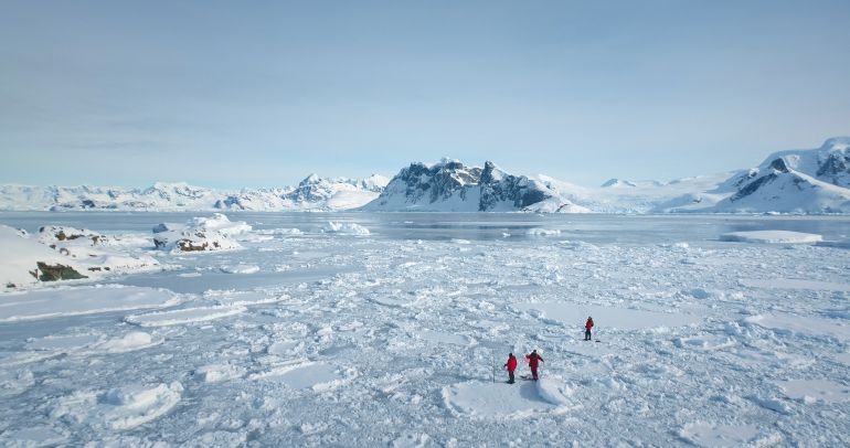 مستشفى المجانين في نهاية الأرض.. ماذا يفعل الشتاء القطبي بعقول البشر؟ 3 People explore Antarctica discover the beauty of South Pole. Expedition, travel and adventure in Antarctic pristine nature. Fly above frozen blue ocean panorama, glaciers and snow covered mountains