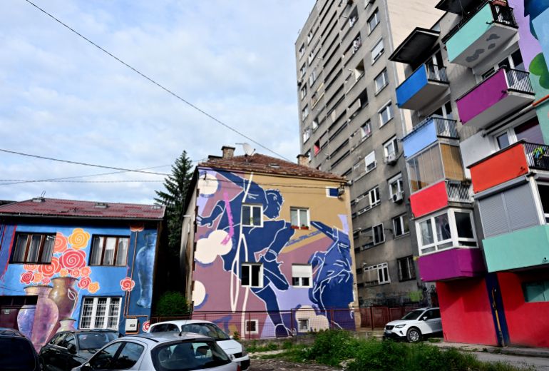 فن الشارع في سراييفو: جسور من الألوان في مواجهة الانقسامات القومية 1 A photo shows the facades of old buildings renovated with murals by Bosnian street artist Benjamin Cengic and his creative team in Sarajevo on May 22, 2025. (Photo by ELVIS BARUKCIC / AFP)