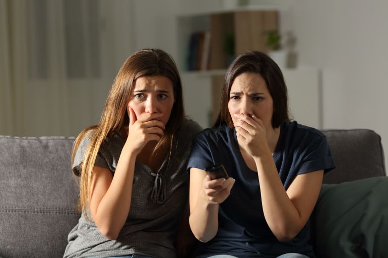 كيف حول الإعلام الأوروبي الخصوصية إلى سلعة جماهيرية؟ 3 Front view portrait of two worried friends watching tv in the night sitting on a couch in the living room at home