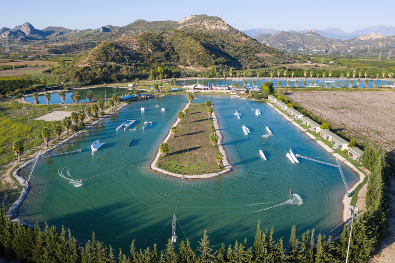 Aerial drone footage of Hip-Notics Cable Park in Antalya, Turkey. Wakeboarding destination in Europe. Wakeboarding on a crystal clear green lake, wakeboard tricks and features of the wake park.
